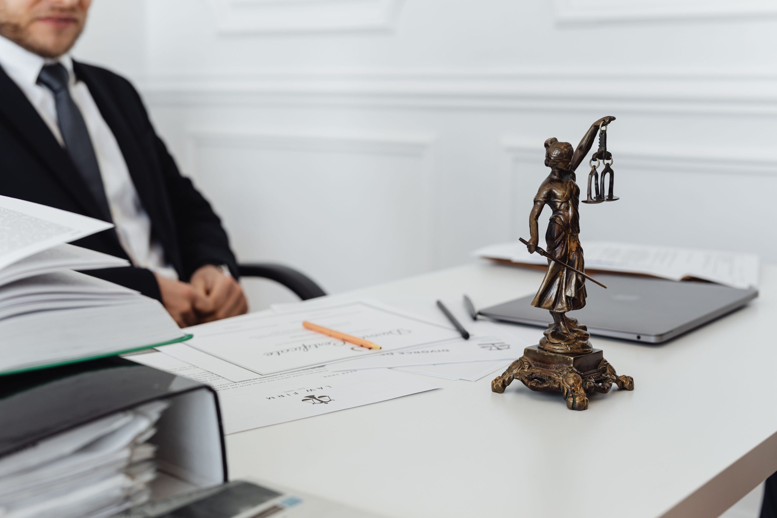 Legal professional's desk with a Lady Justice statue, case documents, and a laptop representing preparation in large-scale litigation
