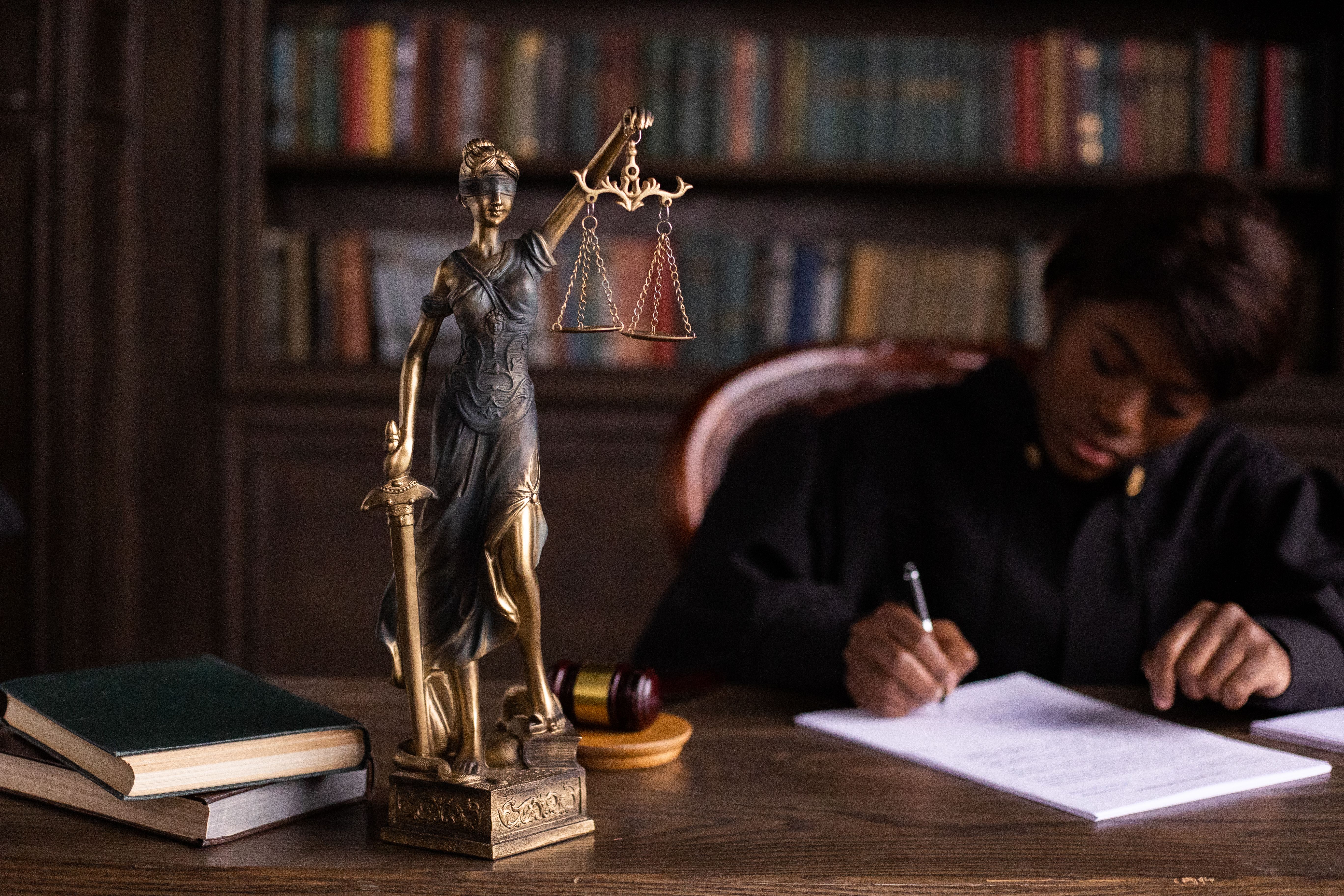 Judge reviewing legal documents beside a Lady Justice statue while managing complex litigation filings