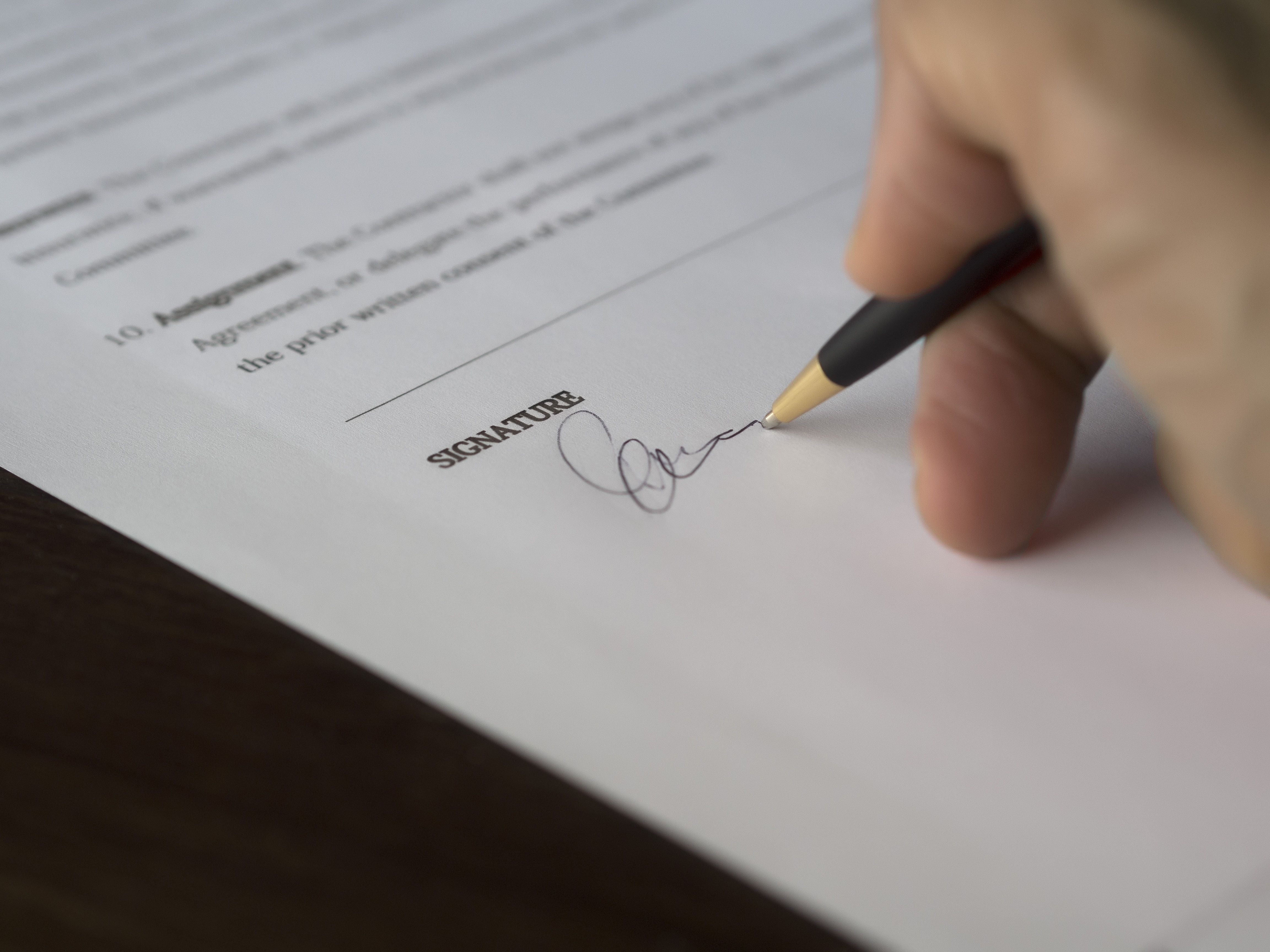 Hand signing a formal settlement agreement with a pen, symbolizing resolution of a large-scale legal claim
